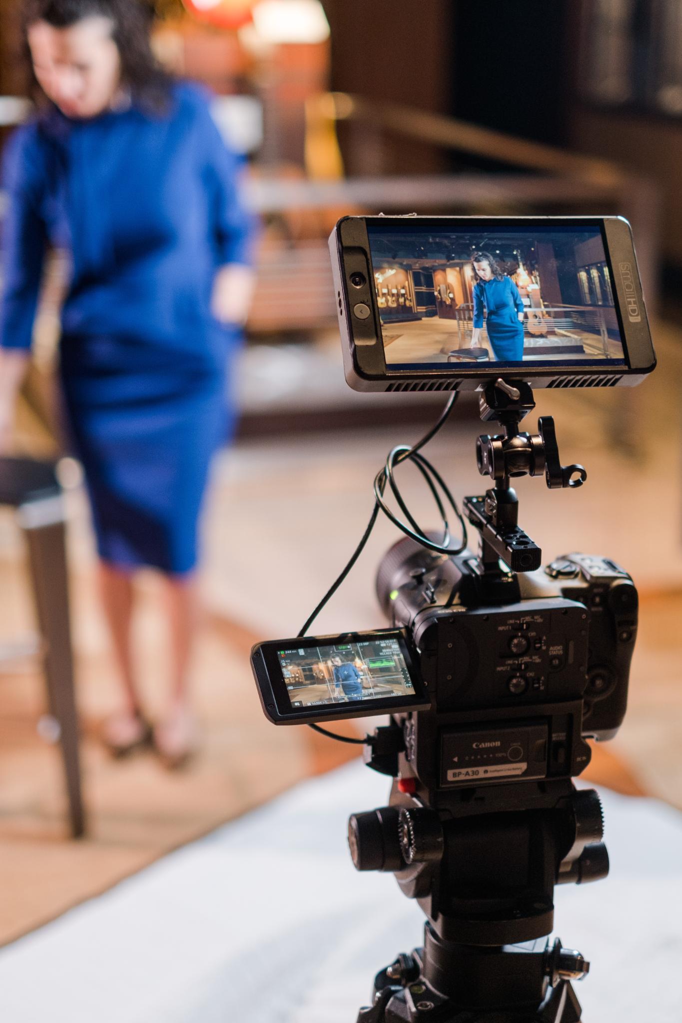 camera with monitor with person in blue dress in background
